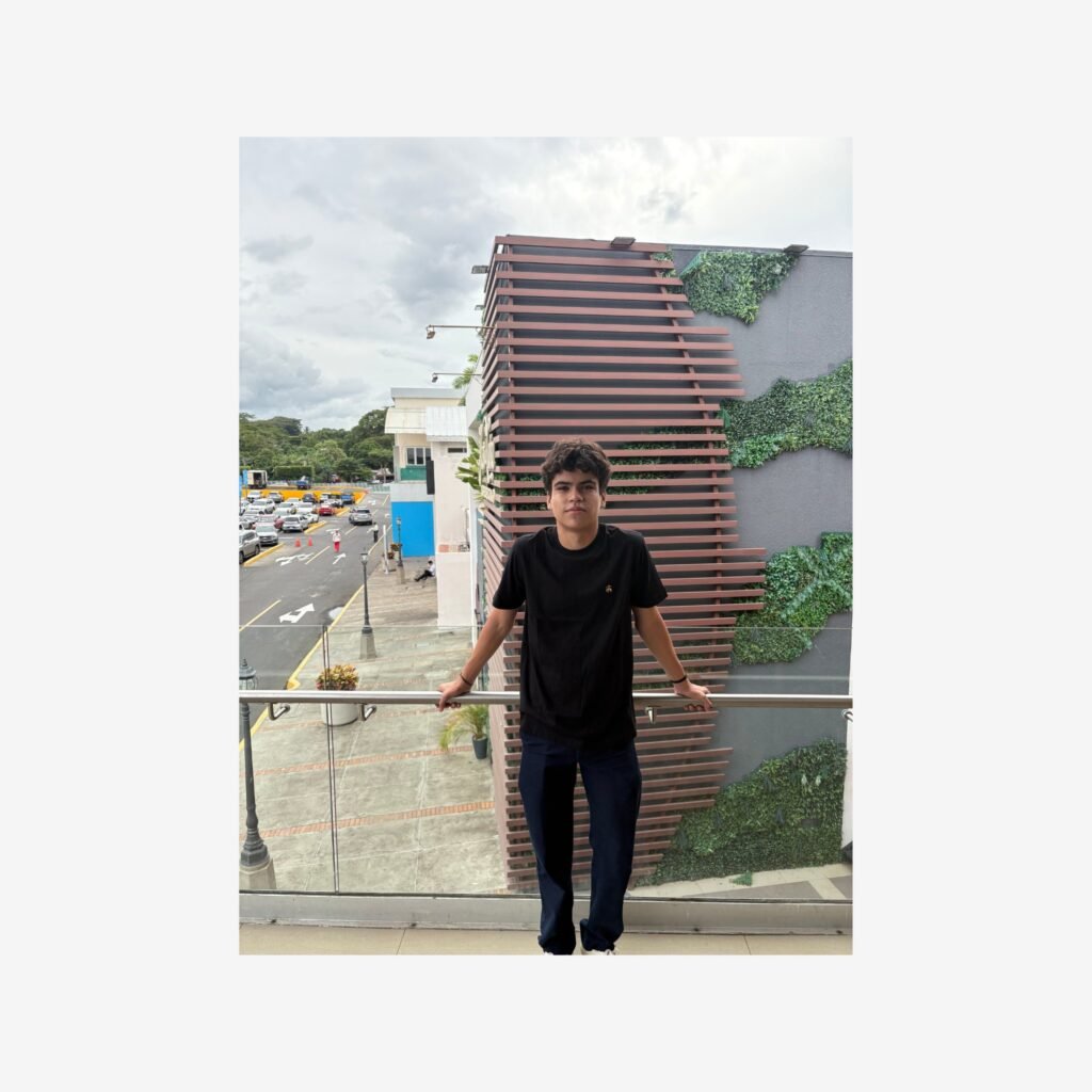 Joven cliente de Marca Elite vistiendo una camiseta negra en un balcón con un fondo urbano en Managua, Nicaragua.